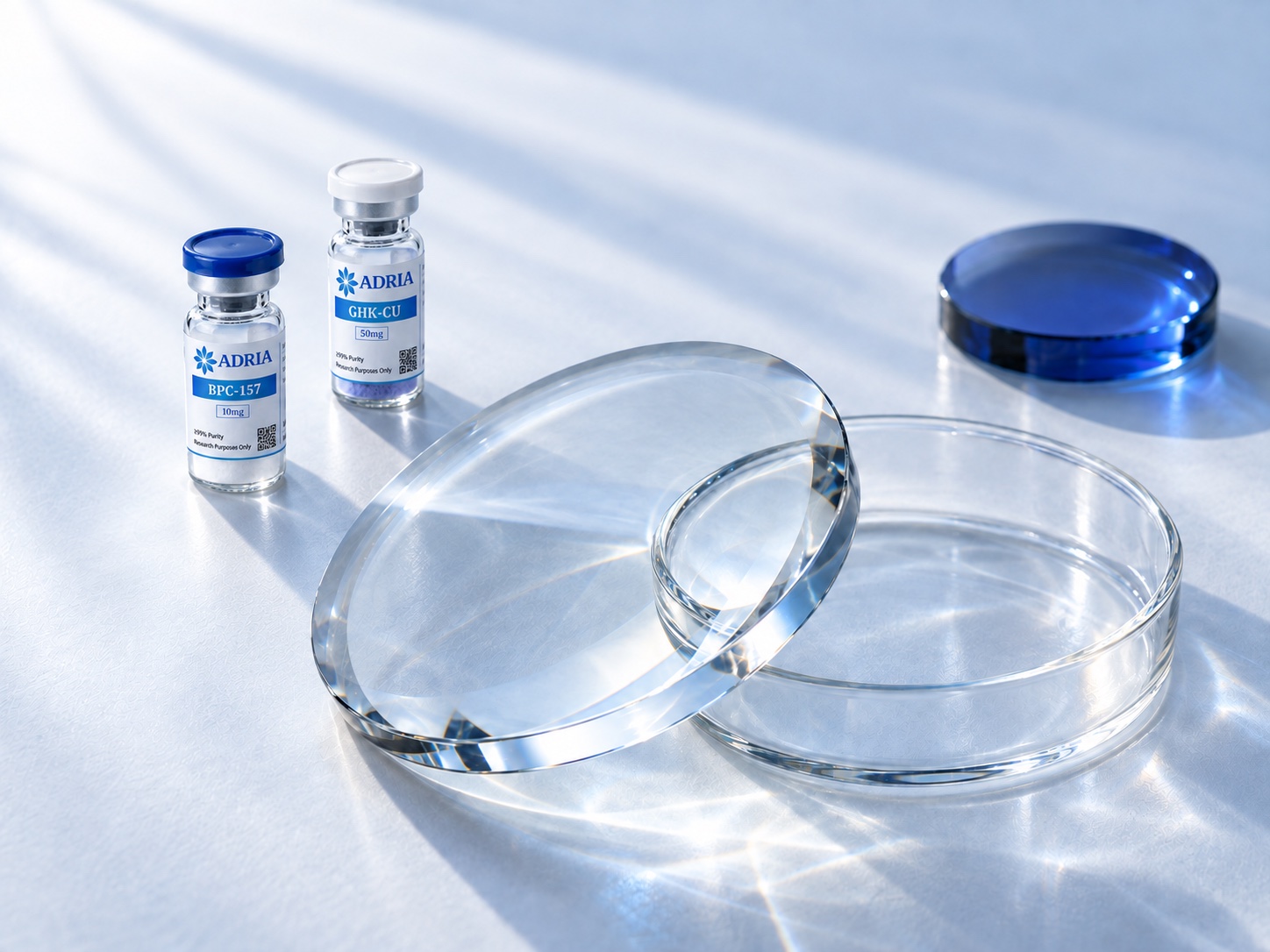 Composition of Adria BPC-157 and GHK-CU vials with clear optical glass in daylight.